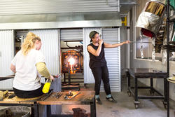 A student blows glass inside the department hot shop