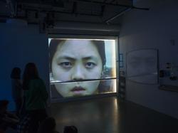 Students watching a large projected face in the dark