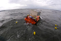 A boat in the sea surrounded by buoys.