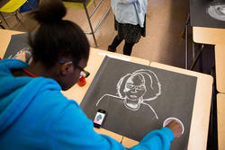 student drawing a portrait on black paper