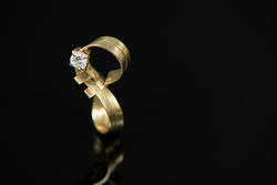 Diamond ring with a gold band shaped like a figure 8 made by a student
