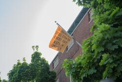 Student work by Emma Werowinski BFA 2018. A flag hanging from a building reading "Congress still starts every day with a prayer"