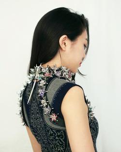 Woman facing away and wearing a jeweled floral chest harness 