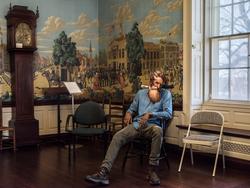 Student work by Jay Simple MFA 2018. Man sitting in a chair with the cutout of a painted face masked over his head.