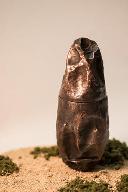 Student artwork of a egg shaped bronze dented sculpture
