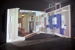 A projection of an image of a foyer and a floor plan on a corner wall