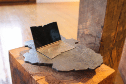 Student artwork displaying a metal sculpture of a laptop displayed on a wooden stand