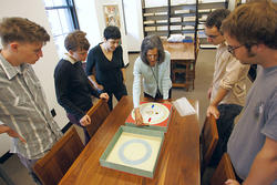 students around a table looking at a piece of art