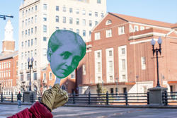 Small paper cutout of Helen Metcalf's head held up in front of RISD buildings