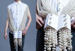 a long beaded necklace draped over a model's shoulders, with a closeup view of the beads exiting a pair of cuffs