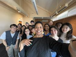 RISD President Crystal Williams poses for a group selfie with 13 students behind her