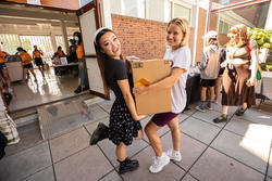 Students hold a box in front of the dorms on move in day