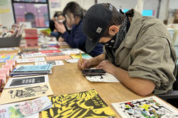 Students sit around a table full of zines at Queer Archive Works and draw