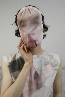 a model wears over their head fabric with the image of a face printed on it, designed by Jeremy Miller