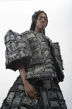 a model wears a puffy quilted gray coat and skirt, all designed by Kyra Buenviaje