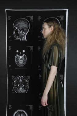 a model stands facing x-rays of a human skull while wearing a black dress by Mariya Kurguzkina