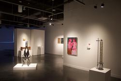 a painting of two pink human figures among other works staged in a gallery