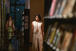 A model walks the runway in the Fleet Library at RISD wearing a shite, shredded-looking garment by Yue Zi