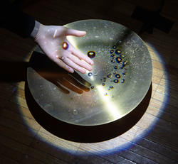 drops of water reflected on someone's hand before hitting a cymbal