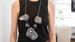 a student models a necklace that appears to be made of large gray stones