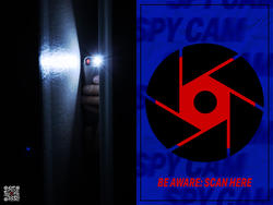 A blue poster with a black and red logo reminiscent of a camera lens and text that reads Be Aware: Scan here in an effort to help the public recognize and report hidden cameras