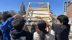 students work together to hoist the completed roof onto the cabin