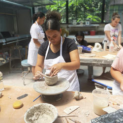 POD student shapes a bowl in intro to clay class in the steel yard