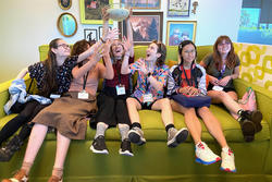 Students sit on a big green couch while taking a playful break from touring at Nickelodeon Animation Studios.