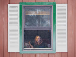 In a self portrait by Sydney Cohn, the viewer peers through a cabin window to see Cohn sitting on the other side and looking into the distance