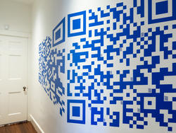 small QR codes visible inside larger blue and white QR code printed on a white hallway wall