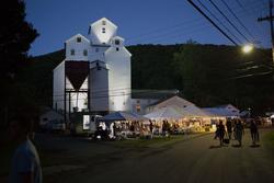 A floodlit farm building at night at a festival.