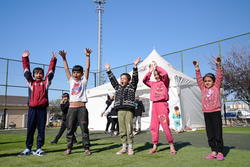 A group of five children in a refugee camp playing a game.