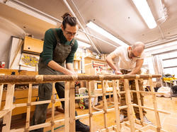 Two students work on a credenza together in the wood shop
