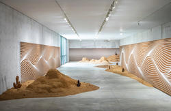 several large patches of orange-brown sand line a long room with walls featuring brown and white wave patterns