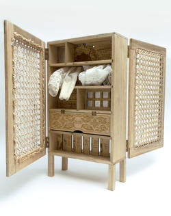 an open wooden box with a door reveals engraved patterns and words and white cloth on a shelf