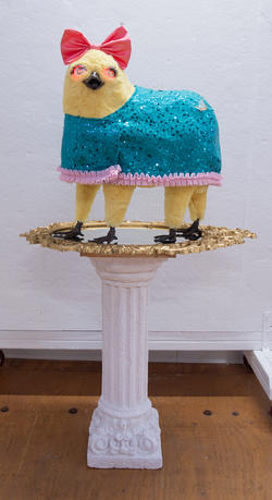 Student work by Illustration graduate alum Simone Nemes of a yellow creature with a pink bow wearing a blue wrap with a pink frill on top of a pedestal.