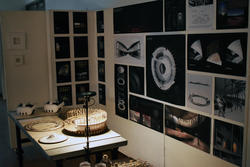 a dimly lit room with virtual reality goggles and a round 3D model on a table and many architectural illustrations on the walls