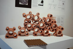 a group of clay modules stand in an interconnected, mutually supporting position on a gallery podium