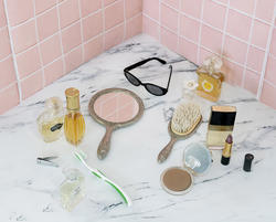 Photo of a cosmetics on white tile in front of a pink-tiled wall