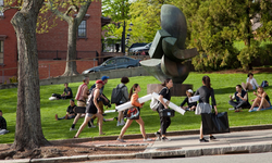 Students walking with large rolls of paper up by the green on benefit street