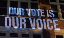 the words "OUR VOTE IS OUR VOICE" projected on a wall