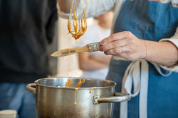 Caramel threads drip from a whisk to a paint brush