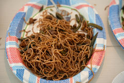A plate of Korean-style noodles sits on a red and blue paper plate