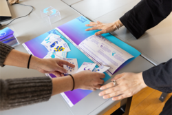 Hands working on a graphic design piece in blues and purples