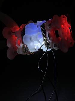 a cylindrical, translucent red and blue device illuminated in a dark space