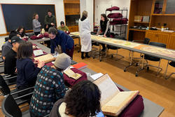 Students observe rare manuscripts in an library room