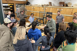 students gather around visiting woodworker Christopher Kurtz