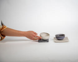 An arm extends out and holds tiles and bowls made out of shells