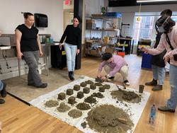 students looking at a grid of clay matter samples on the floor