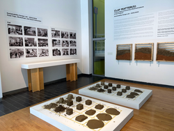 gallery with clay samples in the center of the floor and photography on the walls